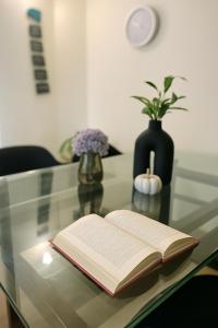 an open book on a glass table with a vase at Meraki - Entire 3BHK Villa With Himalayan Views in Rānīkhet +23 photos