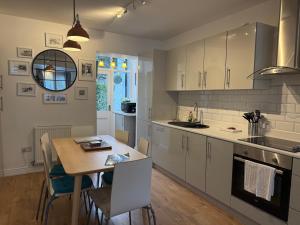 a kitchen with white cabinets and a table with chairs at Downtown Cottage Conwy in Conwy +19 photos