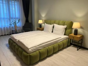 ein Schlafzimmer mit einem großen Bett mit grünem Kopfteil in der Unterkunft Apart Hotel Danaya in Stara Sagora