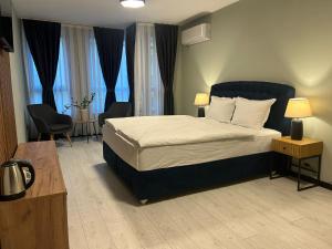 ein Schlafzimmer mit einem Bett und zwei Stühlen und Fenstern in der Unterkunft Apart Hotel Danaya in Stara Sagora