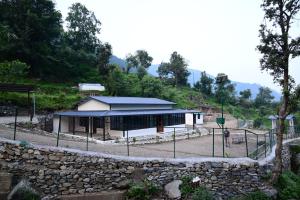 een gebouw met een stenen muur ervoor bij Green View, devalsari in Dhanaulti