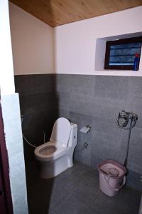 een badkamer met een toilet en een emmer bij Green View, devalsari in Dhanaulti