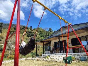 een vrouw die schommelt op een schommel voor een huis bij Green View, devalsari in Dhanaulti