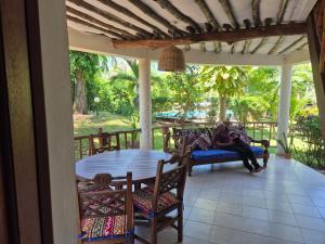 een vrouw op een bank op een veranda bij Petasha Bustani Villas Diani with pool and parking in Galu