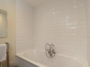 a white bath tub with a shower in a bathroom at Flat 6 in Tetbury +17 photos