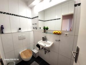 ein weißes Badezimmer mit Toilette und Waschbecken in der Unterkunft Große 3-Zimmer Wohnung, zentrale Lage. in Mülheim an der Ruhr