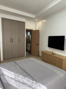 Un dormitorio con una cama grande y un televisor de pantalla plana. en Sublime T2 Lumineux et Calme, en Dakar