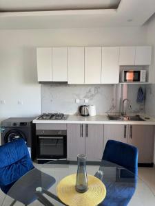 cocina con mesa de cristal y 2 sillas azules en Sublime T2 Lumineux et Calme, en Dakar