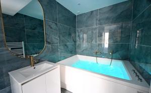 ein Badezimmer mit einer Badewanne und einem runden Spiegel in der Unterkunft Le Sens - Duplex 4 pers - Love Room - Jacuzzi in Sens