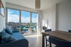 Darsena Ravenna Apartments في رافينا: غرفة معيشة مع أريكة زرقاء ونافذة كبيرة