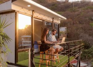 Ein Paar sitzt mit einem Laptop auf dem Balkon eines Hauses. in der Unterkunft Villa Malibu in Taganga