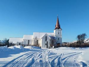 a white church with a steeple in the snow at The Perfect Stop - Northern Halo in Lødingen +19 photos