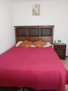 a red bed with two pillows on top of it at Alojamiento Puente Alto in Santiago