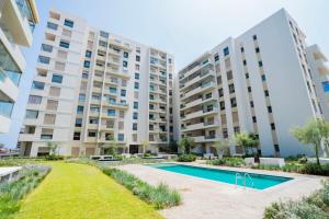 an apartment with a swimming pool and two tall buildings at Luxury Studio in a secured residence in Aïn Harrouda
