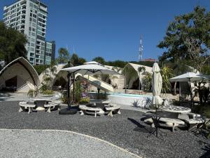 南芭堤雅Camping&Cafe的一个带桌子和遮阳伞的公园和一个游泳池