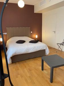 Hôtel Le Riche'Lieu في لوكون: غرفة نوم بها سرير وطاولة