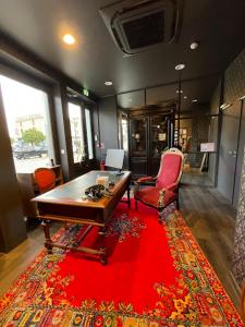 Hôtel Le Riche'Lieu في لوكون: غرفة مع طاولة وكراسي وسجادة حمراء