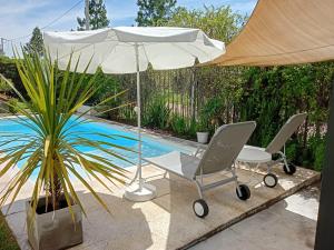 een paar stoelen en een parasol naast een zwembad bij La Aldeana in Gualeguaychú