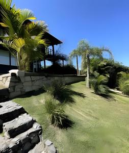 un giardino con palme e un edificio di Casa Fluila a Praia do Rosa