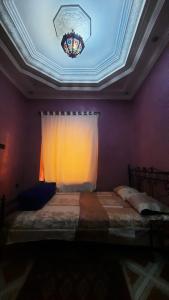1 dormitorio con 1 cama, ventana y techo en Riad Des Artistes, en Oulad Akkou