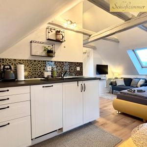 Una cocina con gabinetes blancos y una sala de estar. en Ysenberc Apartments, en Moritzburg