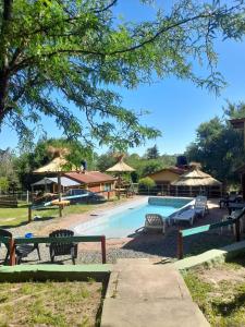 Cabañas Sensaciones Serranas في Casa Grande: مسبح بالطاولات والكراسي والمظلات