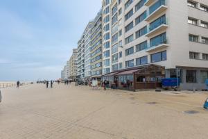 un gran edificio en la playa con gente caminando en Gilles 124, en Ostende