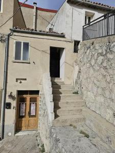 a stone building with stairs leading up to a door at La Casetta nella Roccia in Torricella Peligna