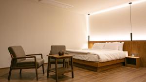 a bedroom with a bed and a chair and a table at Hotel Yimok in Busan