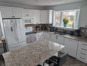 a kitchen with white cabinets and a marble counter top at Waterfront apartment in Gatineau