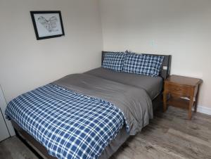 a small bed with a blue and white bedspread and a table at Waterfront apartment in Gatineau