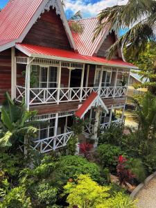 Caye Caulker Boutique Guesthouse 4 في كاي كولكر: منزل بسقف احمر وبعض النباتات