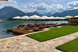 a dock with lounge chairs and umbrellas on a lake at Strandhotel Margaretha in St. Wolfgang