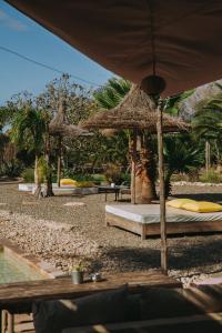 a bed with a straw umbrella on a beach at Les jardins de Silona, piscine chauffée in Essaouira