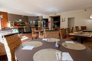 a restaurant with tables and chairs and a kitchen at Le Relais de Vellinus - Contact Hôtels in Beaulieu-sur-Dordogne