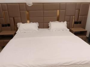 un grande letto bianco con due cuscini sopra di JAMOS House a Kigali