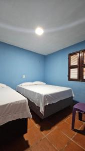 Apartamento com 2 quartos no Chalé Verdelândia - Guaramiranga Ceará في غواراميرانغا: غرفة زرقاء بسريرين ونافذة