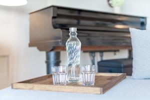 Eine Flasche und zwei Gläser auf einem Holztablett mit einem Klavier in der Unterkunft Gollings am See Gingko-Suite in Bosau + 30 Fotos