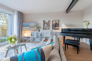 a living room with a couch and a piano at Gollings am See Gingko-Suite in Bosau +17 photos