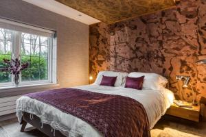 a bedroom with a bed and a stone wall at Gate Lodge in Castle Douglas
