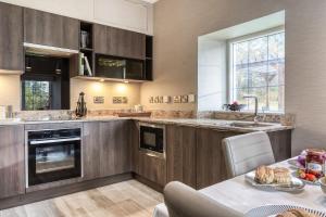 a kitchen with wooden cabinets and a table with food on it at Gate Lodge in Castle Douglas