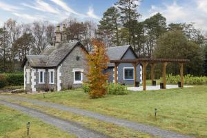 a stone house with a gazebo next to a road at Gate Lodge in Castle Douglas