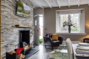 a living room with a stone fireplace and chairs at Courtyard Cottage in Castle Douglas