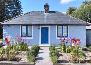 a blue house with flowers in front of it at Courtyard Cottage in Castle Douglas
