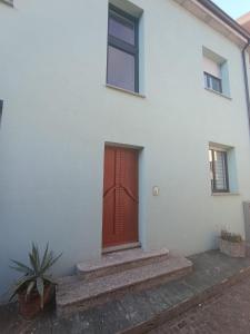 una puerta roja en el lateral de un edificio blanco en Sidera Dafni, en Dervio