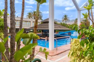 een resortzwembad met een prieel en palmbomen bij Francysara Holiday in Benalmádena