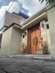 ein Haus mit einer Holztür, die mit Statuen verziert ist in der Unterkunft Cahaya Residence The Guest House in Kuta