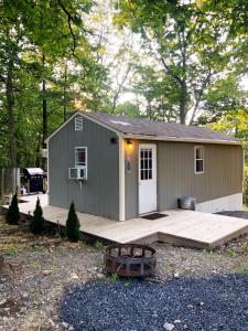 a small green shed with a porch and a deck at Camp Carter Tiny House in Mathias