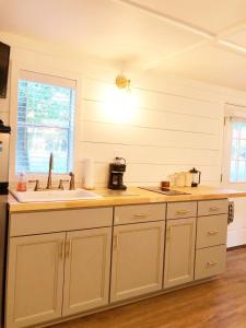 a kitchen with white cabinets and a sink and a window at Camp Carter Tiny House in Mathias +6 photos