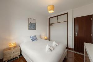 een slaapkamer met een wit bed met 2 kussens erop bij Pérola do Mar in Foz do Arelho